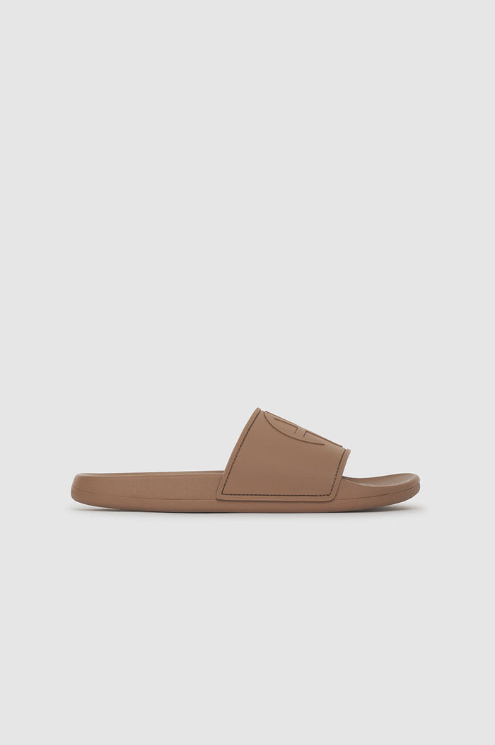 Camel-colored slide sandal with a monogram design on the strap and a flat sole.