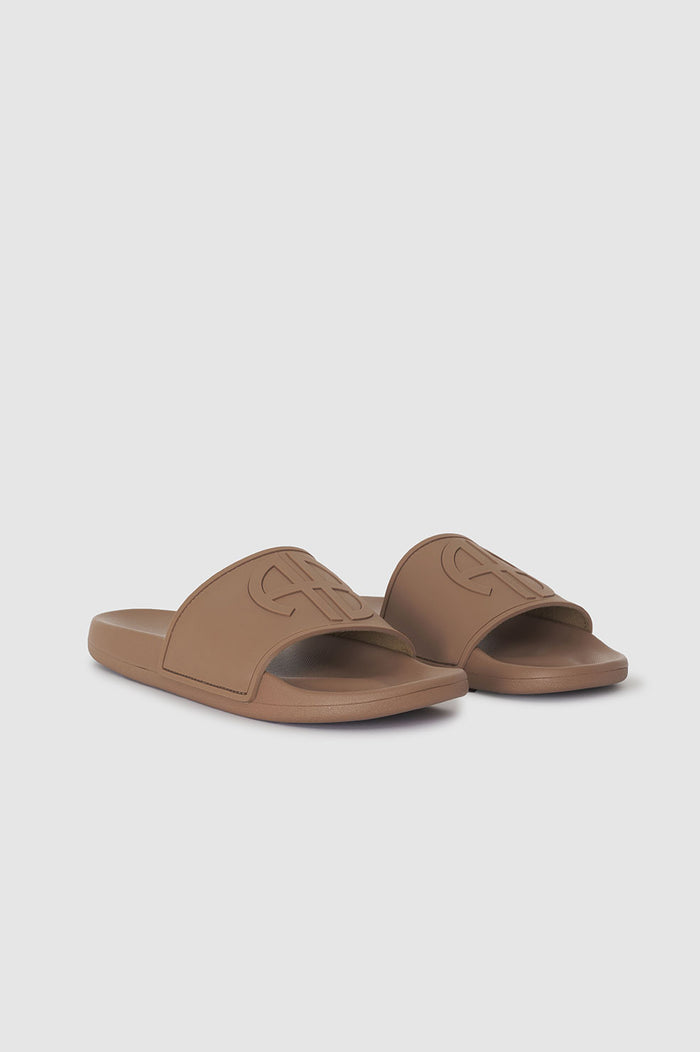 Camel-colored slide sandals with a wide strap featuring a monogram design.